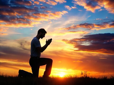 A young man in a praying pose set against a vibrant sunset sunrise sky on his Knees Also related to sacrifice, sanctification, shepherd, trinity, shadow