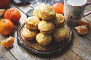 Sweet dessert for breakfast: orange muffins on a wooden table. Orange cupcakes on a wooden board. Close-up.