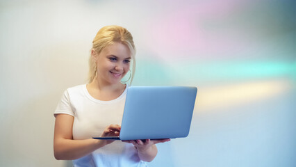 Laptop typing. Happy chat. Social media. Cheerful girl surfing Internet online using browser on modern device remote texting on soft rainbow gradient.