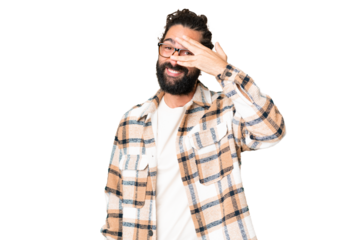 Young man with beard over isolated chroma key background covering eyes by hands and smiling