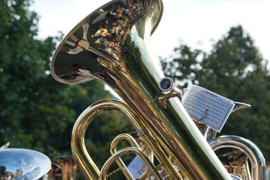 A musical instrument tenorhorn are raised up in the air with musical notes clip on.