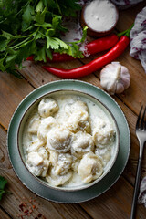 Hearty lunch: Pork dumplings in cream sauce on a plate. Ravioli with meat. Close-up. Vertical photo