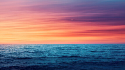 Obraz premium Serene ocean scene with gentle waves under a vibrant sunset sky. The sky has a gradient of warm colors from orange to pink to purple, creating a peaceful atmosphere.