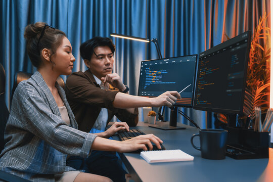 IT developers discussing with point to intelligent website development coder system running data online two screens information technology at neon light room at modern office. Infobahn.