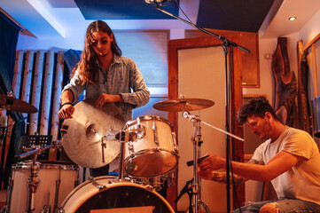 Diverse band members assembling drum parts and a microphones in a music studio