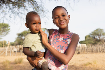 happy village african family child girl and boy standing in front of the pen kraal at the farm