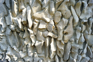 Abstract background: close-up photo of wall surface decorated with light unprocessed stone. Building design using natural materials.
