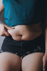 Fototapeta premium fat woman, fat belly, chubby, obese woman hand holding excessive belly fat with measure tape, woman diet lifestyle concept