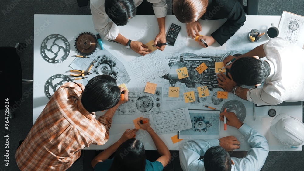 Poster top view of smart engineer team in casual cloth talking about turbine engine structure at table with
