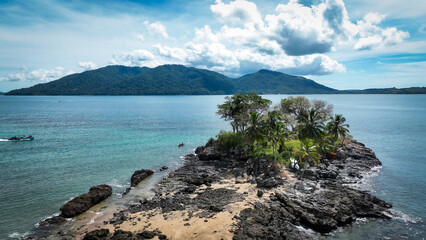 Aerial view of Nosy Komba Island in Madagascar showcasing its lush greenery, rocky coastline, and serene waters under a bright blue sky