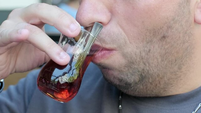 Close-up video of a man sipping hot tea from a traditional glass. The video focuses on the gentle sip, showcasing the cultural tea experience