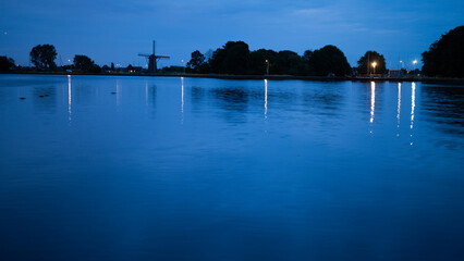 Sunset over the river with the mill in the background under the blue sky in Leiden, the Netherlands