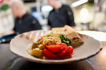 A close-up of a plated meal featuring a quesadilla, cherry tomatoes, and a side of salad, served in a restaurant setting. Perfect for food blogs, menus, or culinary websites.