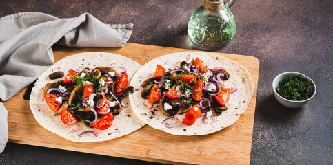Delicious tacos with fried mushrooms, tomatoes, onions and feta on a board web banner