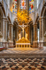 The interior of the Church of Saint-Merri features beautiful stained glass windows and a striking altar adorned with sculptures and a large crucifix, showcasing intricate architectural details.
