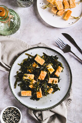 Seaweed salad with fried soy tofu cheese on plate on table top and vertical view