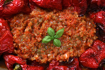 tomato and onion sauce with herbs close-up and sweet peppers around