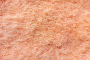 Peach plush knitted fabric texture close up. Fluffy and soft cozy fabric background. 