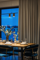 Dining room with table setting against city view on window at night