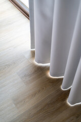 White curtain draped over hardwood floor in room