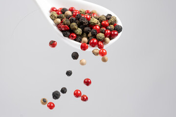 Different types of peppercorns pouring. Red, green, white and black pepper.