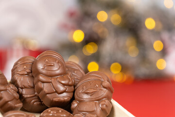 Chocolates in the shape of Christmas figures on the background of a flashing garland