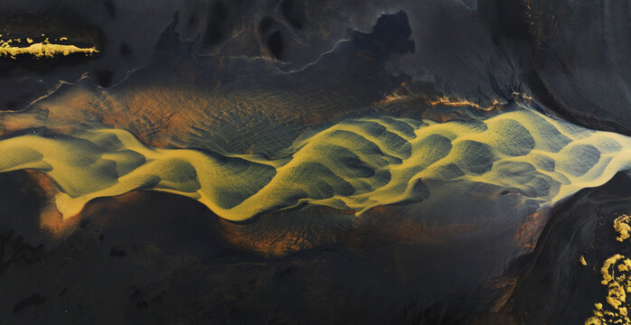 Beautiful Icelandic yellow river flowing into black sand beach