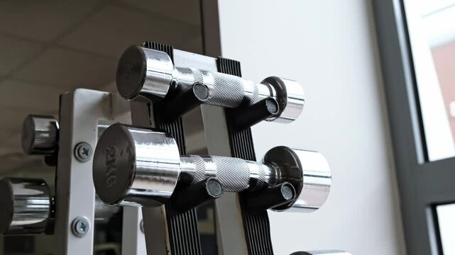A Dumbbell Rack in Fitness Gym. Set of steel dumbbells of different weight from light to heavy. Sport equipment for strong arm muscles. No people. Sporty lifestyle concept. High quality 4k footage