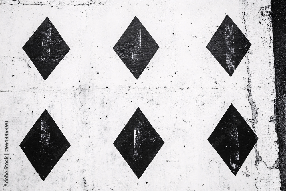 Aufkleber abstract pattern of black diamond shapes painted on a white wall with a rough texture creating a sta