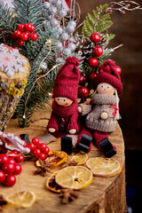 cute New Year composition with toy men in knitted clothes with dried lemons, Christmas tree and fir branches, Christmas entourage vertically, fairytale postcard