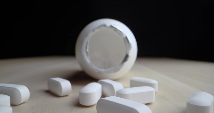4k 60fps dolly shot of a prescription pill bottle spilled on a table, starting from outside the bottle zooming in