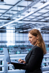 Data center system administrator ensuring safety and security of database using laptop. IT staff...