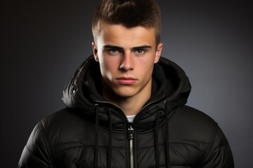 Fototapeta premium A young man in a black jacket with a hood over his head