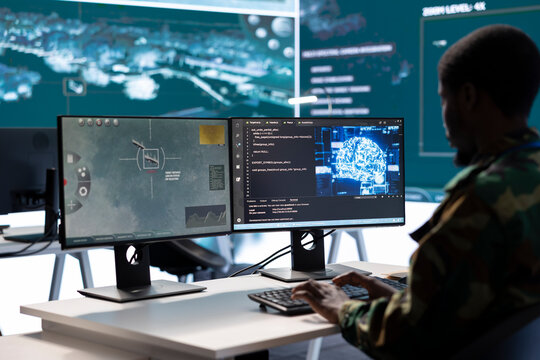 Soldier working with AI intelligence on pc in control room, processing live data on cctv satellite systems. Surveillance efforts to support field missions and defense operations, national security.