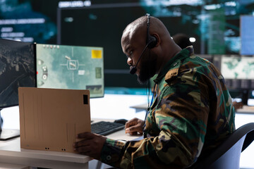 Military professional in a mission control center monitors satellite data feeds, communicating real...