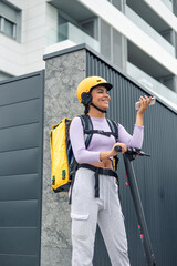 vertical smiling latin food delivery girl talking on phone while on electric scooter