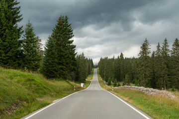 une route sans fin en montagne sous un ciel orageux