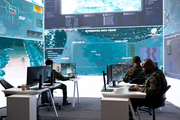 Army staff in a high tech control room managing crucial defense information, gathering live...