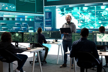 Hackers team engaging in governmental espionage and using phishing techniques for illegal access to data, working on national security breach. Spyware agency gains access on a big screen.