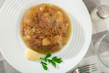 Traditional russian meat aspic dish kholodets on plate with mustard and parsley.