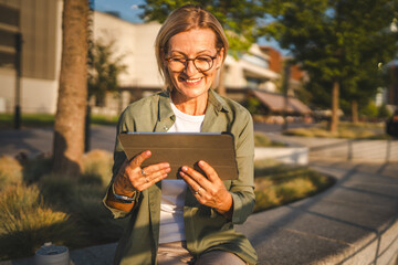 mature woman use digital tablet in front trees outdoor
