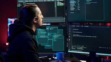Hacker typing fast on keyboards, rushing to finish developing spyware software, using it to gather...