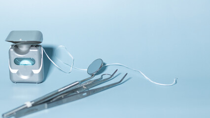 Dental instruments on blue background with floss