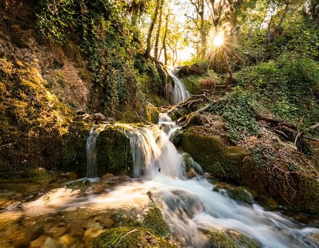 Small waterfall in the forest flowing from the mountains through rocky terrain.