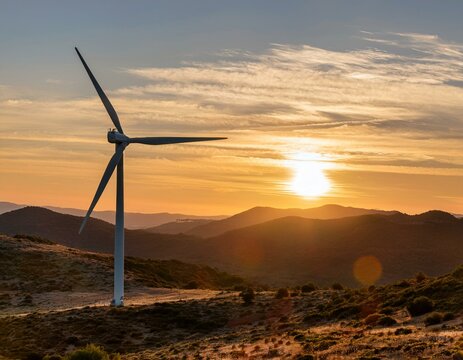 Wind power generator with background of the mountains during beautiful sunset.