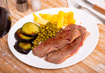 Traditional grilled beef meat and vegetables with french fried on a plate in a cafe