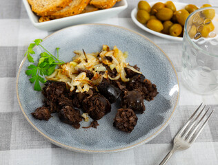 Delicious fried morcilla (blood sausage with rice) and grilled onion with parsley served on plate....