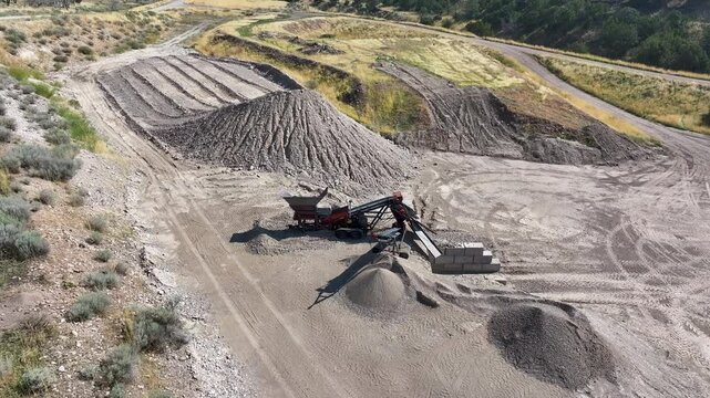 Aerial industrial rock crusher rural hills Utah pull. Industrial construction manufacturing facility. Rocks crushed into gravel for concrete, building, road base. Gravel pit manufacture rocks.
