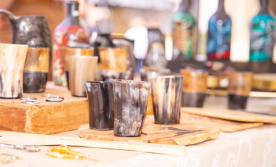 Handcrafted horn cups, wooden serving boards, artisan market display, colorful bottles, traditional craftsmanship, handmade concept