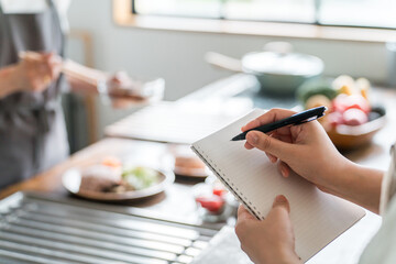 料理教室・クッキングスクールで料理を教わりメモを取る女性生徒の手元
